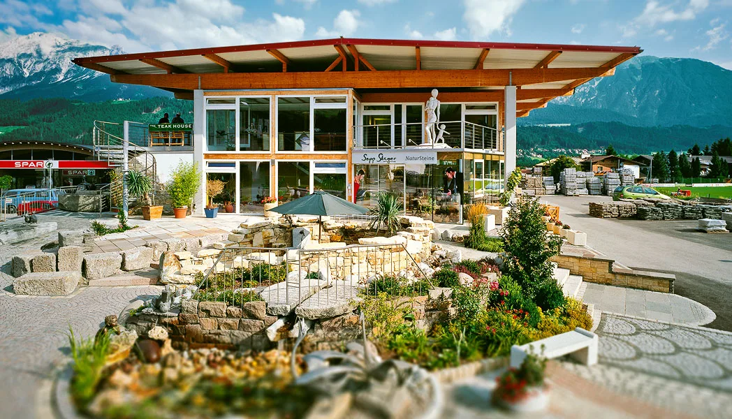 Firmengebäude mit Schauraum und angelegtem Schaugarten vor Bergkulisse